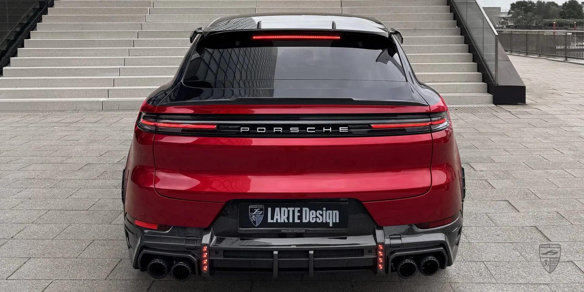 Red Porsche Cayenne Coupe in body kit within an urban cityscape setting