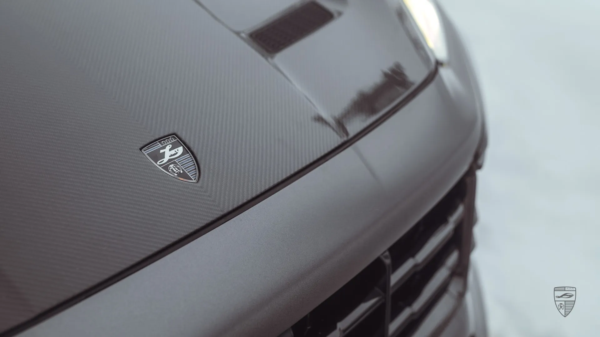 Detailaufnahme der verkleideten Haube am Porsche Cayenne in mattgrauer Folierung mit Premium‑Carbon